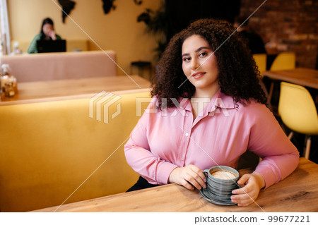 Portrait of a beautiful plump woman drinking a cup of coffee in a cafe. Portrait of a beautiful plump woman drinking a cup of coffee in a cafe. 99677221