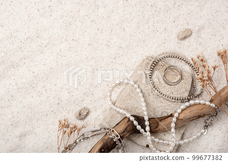 Beautiful Silver and Pearl Jewelry on white stones and sand. Various jewelry - bracelets, necklaces and rings. Place for text. Beautiful Silver and Pearl Jewelry on white stones and sand. Various jewelry - bracelets, necklaces and rings. Place for text. 99677382
