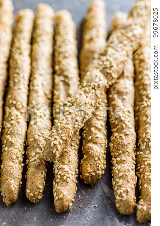 Italian grissini bread sticks with sesame seeds on kitchen table. 99678025