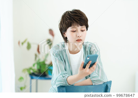 A young woman operating a smartphone 99678647