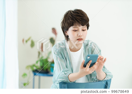 A young woman operating a smartphone 99678649