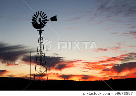 The silhouette of a windmill towering over the wilderness and the vivid sky The silhouette of a windmill towering over the wilderness and the vivid sky 99678897