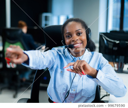 Young african woman talking to a client on a headset. Happy female call center employee.  99679590