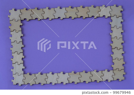Purple background with a frame made of wooden puzzles. Copy space for text. Flat lay, top view. 99679946