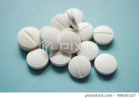 white color medical pills spilling on pink  99680187