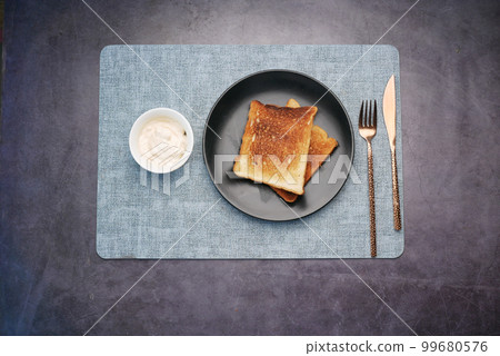top view of milk cream in a container and bread in a plate  99680576