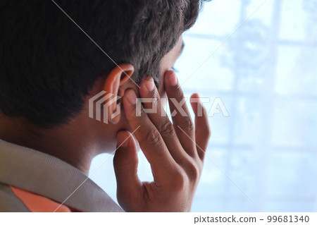 teenage boy having ear pain touching his painful ear , 99681340