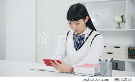 Female student studying while looking at her smartphone Online class e-learning Female student studying while looking at her smartphone Online class e-learning 99682056