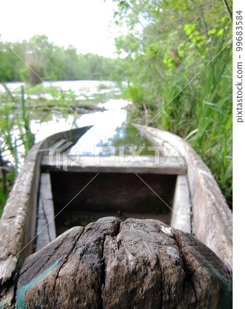 Old wooden broken boat for swimming on banks water in natural reeds 99683584