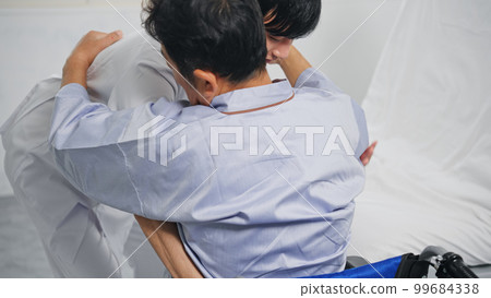 Caregiver assisting transfer from bed to wheelchair Caregiver assisting transfer from bed to wheelchair 99684338