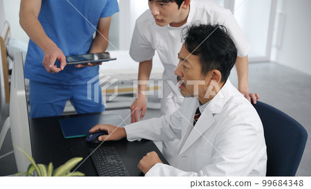 Group of medical workers in a meeting looking at a computer 99684348