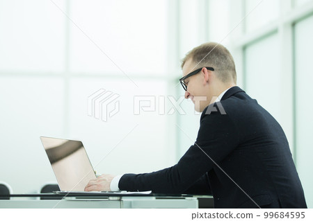 smiling businessman working on laptop in office. smiling businessman working on laptop in office. 99684595