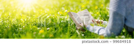 Woman lying on the blossoming meadow with book in her hands. Woman lying on the blossoming meadow with book in her hands. 99684918