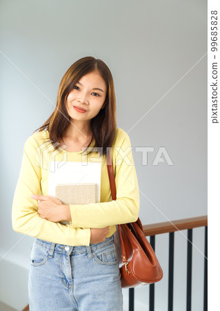 Education and literacy concept, College student girl stand to holding a book and crossing her arms Education and literacy concept, College student girl stand to holding a book and crossing her arms 99685828