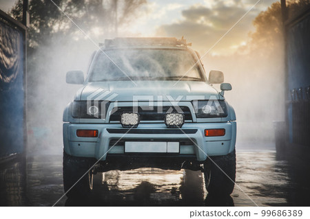 Front view of self-service car wash with box in which the white car are in the process of washing 99686389