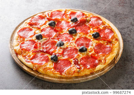 Delicious classic Pizza Devil with pepperoni sausage, cheese, tomato sauce, chili peppers and black olives close-up on a wooden board. Horizontal Delicious classic Pizza Devil with pepperoni sausage, cheese, tomato sauce, chili peppers and black olives close-up on a wooden board. Horizontal 99687274