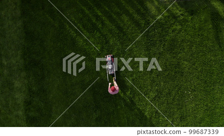 Professional worker with lawn mower mows the grass, top view. Copy space 99687339