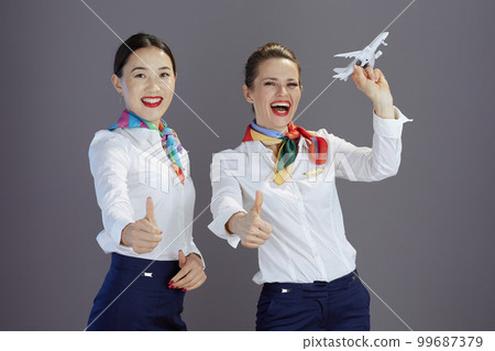 happy stylish female air hostesses isolated on grey background happy stylish female air hostesses isolated on grey background 99687379