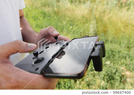 Control panel with a smartphone in the hands of a drone pilot outdoor Control panel with a smartphone in the hands of a drone pilot outdoor 99687400
