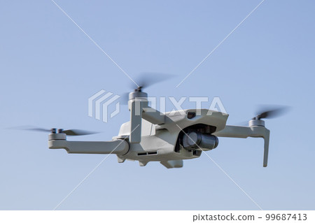 Quadcopter aka drone hangs in the air against the blue sky, copy space 99687413