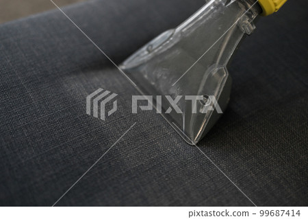 Man dry cleaner's employee hand in protective rubber glove cleaning sofa with professionally extraction method. Early spring regular cleanup. Commercial cleaning company concept 99687414