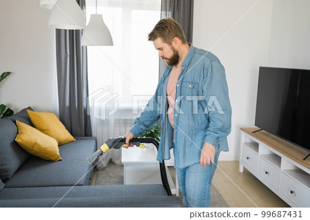 Man in protective rubber glove cleaning sofa with professionally extraction method with washing vacuum cleaner. Early spring regular cleanup. Commercial cleaning company concept 99687431