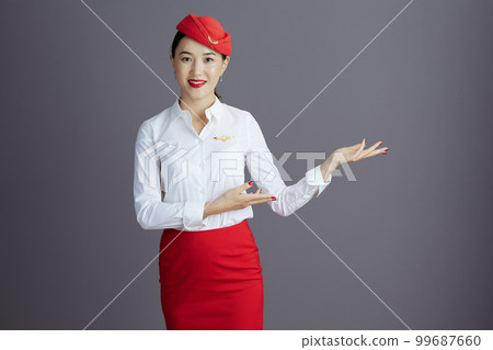 smiling air hostess asian woman welcoming isolated on grey 99687660