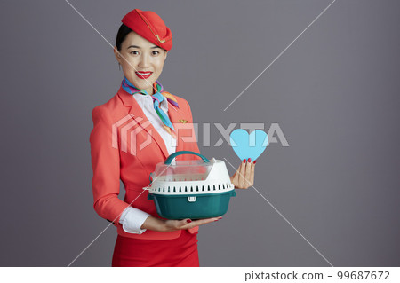 smiling stewardess asian woman showing heart against grey 99687672