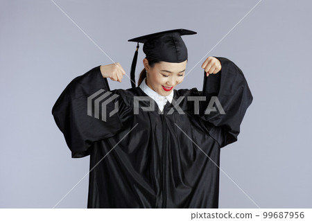 female asian graduate student showing biceps isolated on gray 99687956