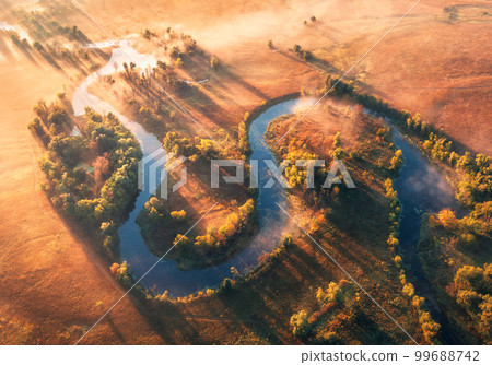 Aerial view of curving river in fog at sunrise in autumn Aerial view of curving river in fog at sunrise in autumn 99688742