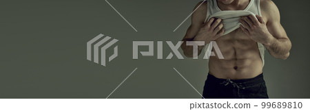 Cropped image of muscular relief body, torso. Male model posing in singlet over green studio background. Concept of men's health, beauty, sport. Banner Cropped image of muscular relief body, torso. Male model posing in singlet over green studio background. Concept of men's health, beauty, sport. Banner 99689810