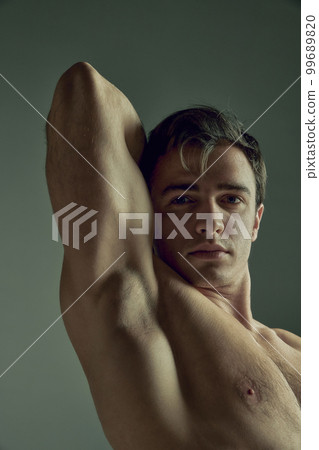 Full-length image of handsome young man with muscular relief body shape posing shirtless in black pants over green studio background. Concept of men's health, beauty, sport Full-length image of handsome young man with muscular relief body shape posing shirtless in black pants over green studio background. Concept of men's health, beauty, sport 99689820