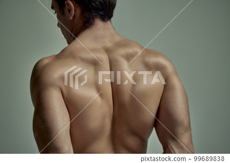 Cropped image of strong muscular male body, shoulders, relief back over pale green studio background. Male model posing shirtless. Concept of men's health, beauty, sport 99689838