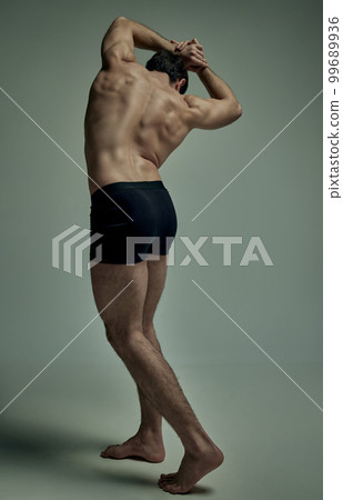Healthy spine. Full-length image strong man with muscular body, relief back posing shirtless over pale green studio background. Concept of men's health, beauty, sport Healthy spine. Full-length image strong man with muscular body, relief back posing shirtless over pale green studio background. Concept of men's health, beauty, sport 99689936