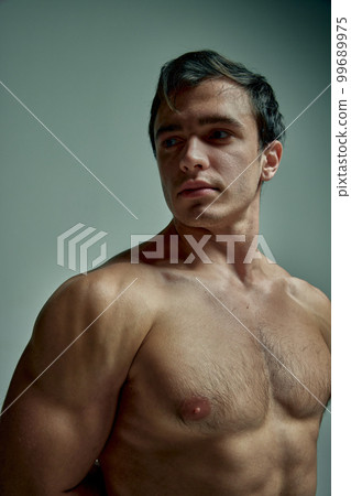 Relief shoulders. Portrait of handsome young man with muscular body posing shirtless over pale green studio background. Concept of men's health, beauty, sport Relief shoulders. Portrait of handsome young man with muscular body posing shirtless over pale green studio background. Concept of men's health, beauty, sport 99689975
