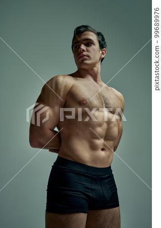 Relief body shape. Handsome young man with muscular body posing shirtless in black underwear over studio background. Concept of men's health, beauty, sport Relief body shape. Handsome young man with muscular body posing shirtless in black underwear over studio background. Concept of men's health, beauty, sport 99689976