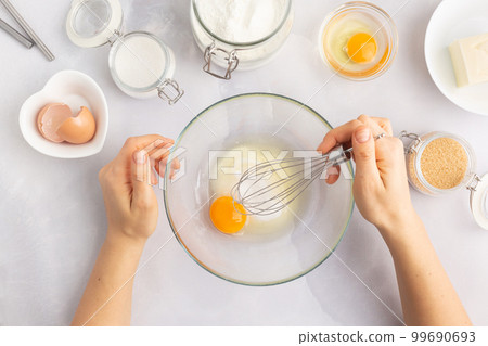 Various baking ingredients - flour, eggs, sugar, butter and kitchen utensils on grey background Various baking ingredients - flour, eggs, sugar, butter and kitchen utensils on grey background 99690693
