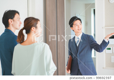 A young man who is a real estate salesman who guides a couple in their 30s to a model house 99692397