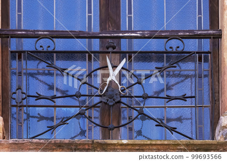 Old scissors on the grated window of a sewing workshop Old scissors on the grated window of a sewing workshop 99693566