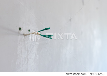 three insulated electrical wires on a white plastered wall 99694250