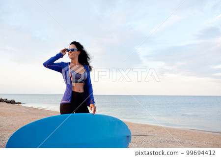 Optimistic woman in bikini with surfboard going to catch a wave, surfing, having fun on the beach, surfing on vacation 99694412