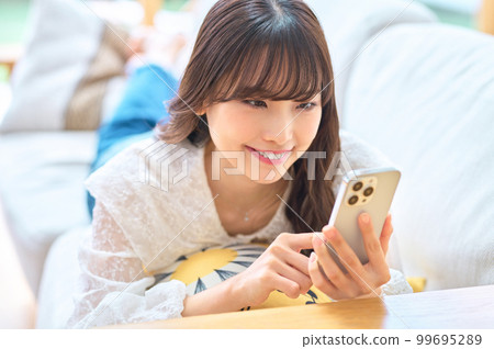 Young woman doing a smartphone in the living room 99695289