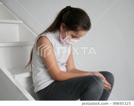 Student girl wearing a mask seating on stairs after COVID-19 quarantine and lockdown, sad and tired of not going to school with her friends. 99695325