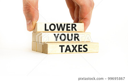 Lower your taxes symbol. Concept words Lower your taxes on wooden blocks on a beautiful white table white background. Businessman hand. Business tax lower your taxes concept. Copy space. Lower your taxes symbol. Concept words Lower your taxes on wooden blocks on a beautiful white table white background. Businessman hand. Business tax lower your taxes concept. Copy space. 99695867
