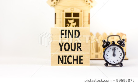 Find your niche symbol. Concept words Find your niche on wooden blocks. Black alarm clock. Beautiful white table white background. Business and find your niche concept. Copy space. 99695873