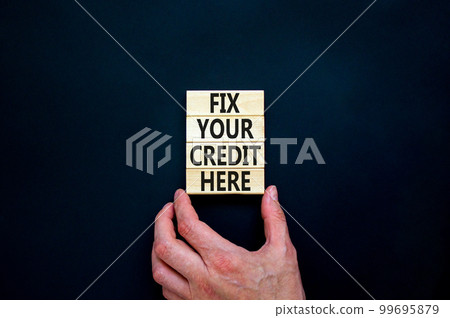 Fix your credit here symbol. Concept words Fix your credit here on wooden blocks on a beautiful black table black background. Businessman hand. Business, finacial and fix your credit here concept. 99695879
