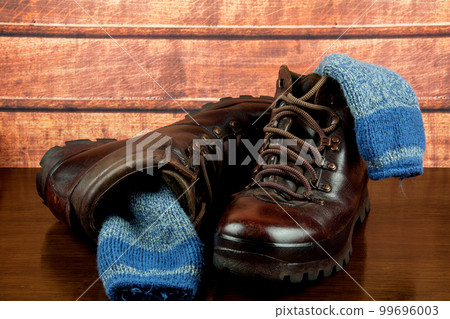 Old Hiking Boots and Socks on a Wooden Table Top Old Hiking Boots and Socks on a Wooden Table Top 99696003