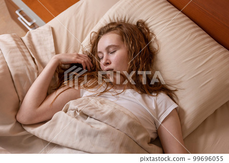 A girl very tired with her mouth open sleeps soundly on the bed 99696055