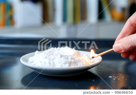 Hand ignites urotropin mixed with calcium gluconate. Concept of chemistry lesson, chemical experiment 99696650