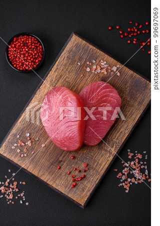 Two fresh slices of raw tuna fillet with spices and herbs Two fresh slices of raw tuna fillet with spices and herbs 99697069